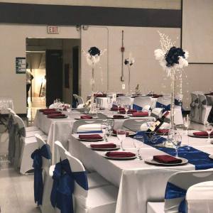 Event hall decorated with white linens, blue sashes, and burgundy accents, decor rental by Decorentals2go Ottawa