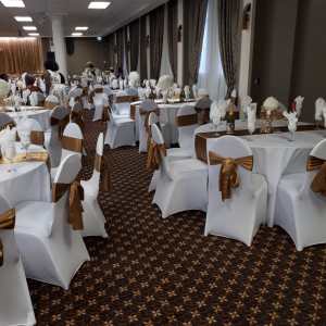 Event hall decorated with white linens and gold chair sashes for a formal event, decor rental by Decorentals2go Ottawa